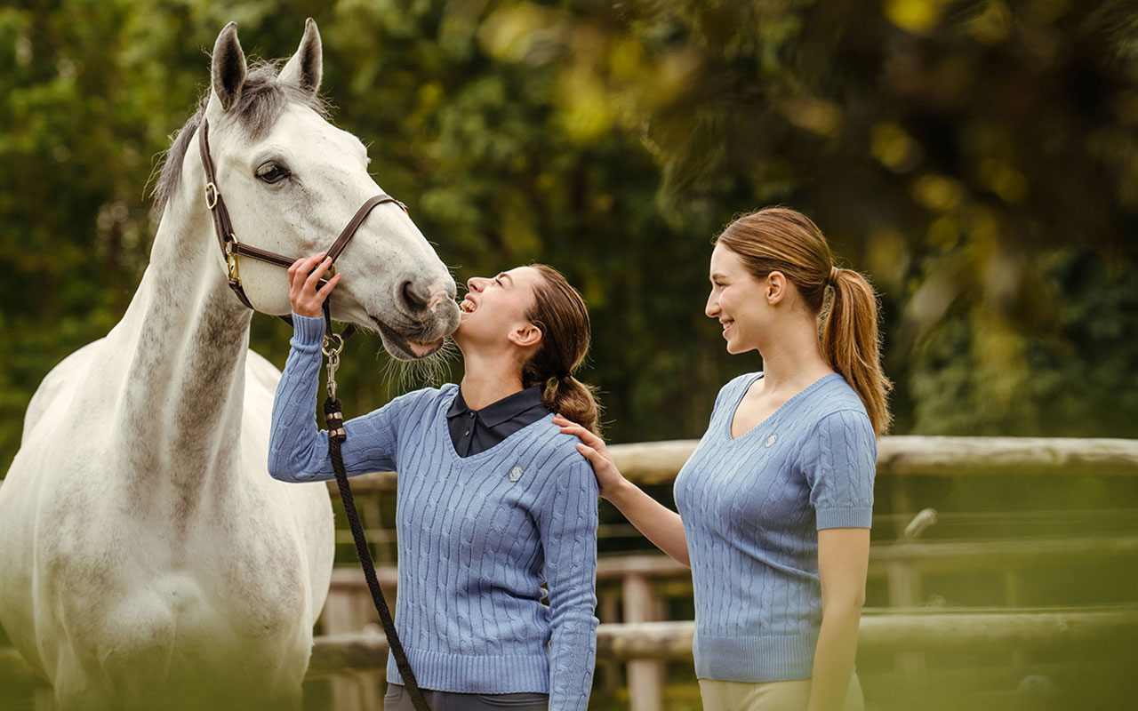 Zwei Frauen mit Samshield Oberbekleidung und einem weißen Pferd