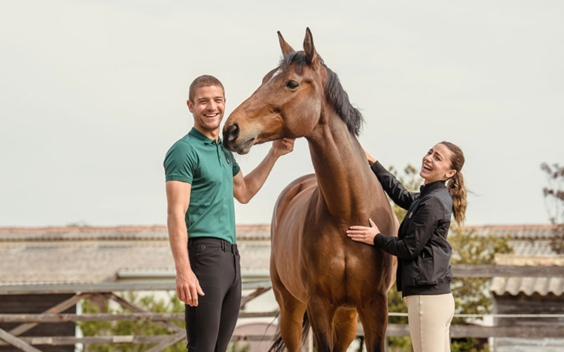 Mann und Frau mit einem braunen Pferd zwischen ihnen tragen Samshield Kleidung
