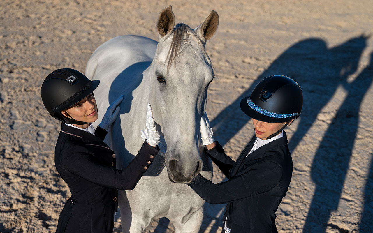 Zwei Reiterinnen im Samshield Turnieroutfit mit weißem Pferd