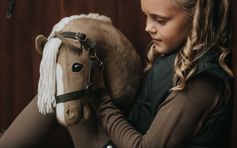 Kind mit Hobbyhorse in Sattelkammer